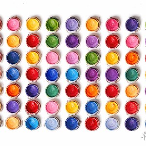 Pu&ograve; includere: Una griglia di settantadue vasetti di vernice circolari disposti in otto colonne e nove righe. Ogni vasetto contiene un colore solido diverso, incluse tonalit&agrave; di rosso, arancione, giallo, verde, blu, viola e rosa, con un piccolo logo nell'angolo.