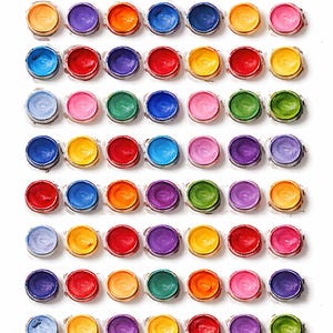 May include: A top-down view of a grid of small, open paint pots. The pots are arranged in rows and columns, each filled with a different vibrant color, including red, orange, yellow, green, blue, and purple. The background is white.