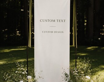 Może przedstawiać: Wysoki, prostokątny baner z białej tkaniny zawieszony na czarnej metalowej ramie. Na banerze znajduje się czarny nadruk z tekstem CUSTOM TEXT oraz CUSTOM DESIGN. Dwie oliwkowozielone wstążki są przywiązane do górnych rogów ramy.