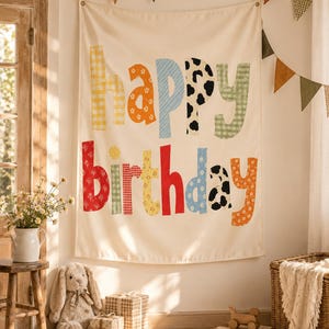 Może przedstawiać: Kremowa tkanina ścienna z napisem "happy birthday" wykonanym z dużych, wielokolorowych liter o r&oacute;żnych wzorach. Każda litera ma unikalny nadruk, w tym kratkę vichy, kwiaty, łaty krowie oraz paski w odcieniach czerwieni, pomarańczu, ż&oacute;łci, błękitu i zieleni.