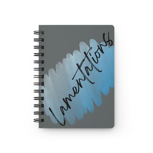 Puede incluir: Un cuaderno con espiral con una cubierta gris. La cubierta presenta un diseño de pincelada azul y azul claro al estilo acuarela con la palabra "Lamentations" en escritura negra. El cuaderno tiene una encuadernación en espiral negra.
