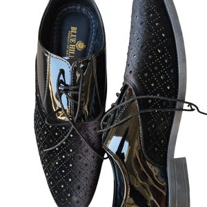 May include: Pair of black dress shoes with a glossy patent leather toe and a textured, perforated design on the sides. The shoes have laces and a low heel. The brand name "BLUE HILL" is visible on the insole. The text "Leatherluxearts" is at the bottom.
