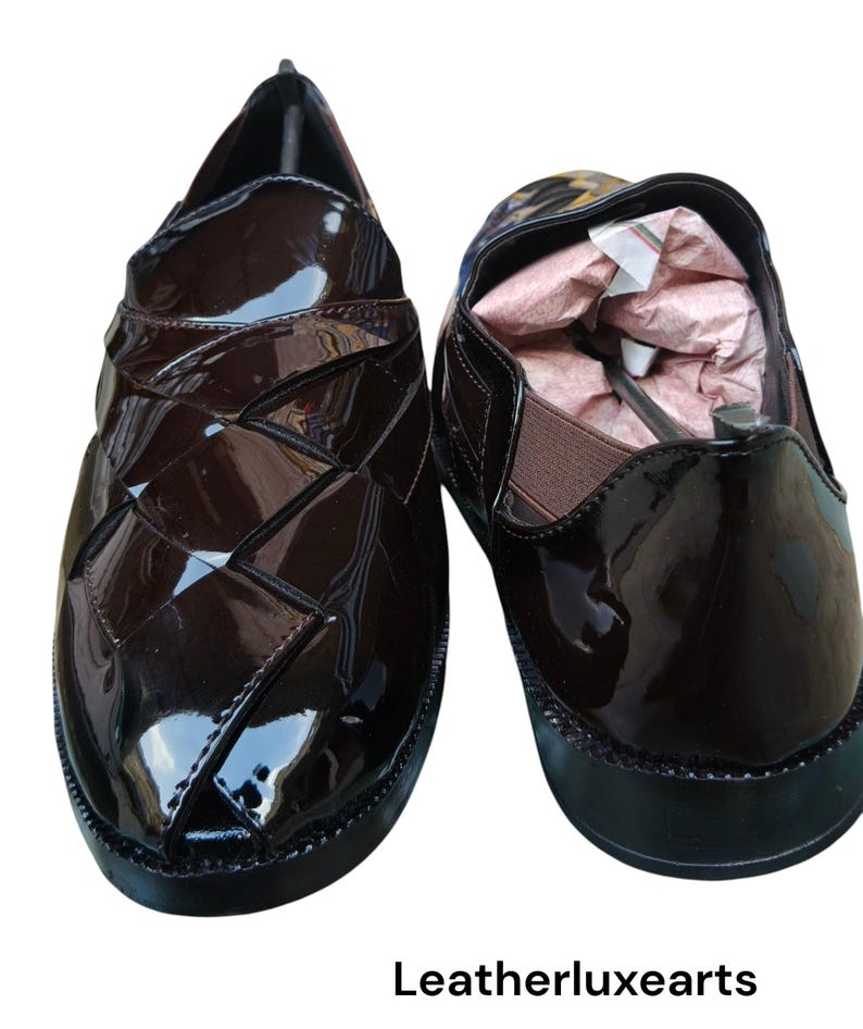 May include: A pair of dark brown patent leather slip-on shoes with a woven-style upper design, black soles, and elastic side panels. The interior of the right shoe contains pink paper stuffing. The text "Leatherluxearts" appears below the shoes.