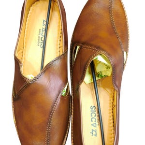Puede incluir: Un par de zapatos de cuero marr&oacute;n con dise&ntilde;o sin cordones. Los zapatos tienen un patr&oacute;n cosido y un corte lateral. La marca "SICCIS" es visible en la plantilla. El texto "Leatherluxearts" est&aacute; en la parte superior.