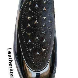 May include: Black patent leather loafer with a velvet vamp. The vamp is decorated with silver-tone triangle studs and small round studs. The shoe has a glossy finish and a rounded toe. The text "Leatherluxearts" is on the side.