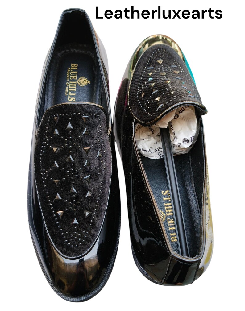 May include: Pair of black patent leather loafers with a velvet vamp adorned with silver-tone studs. The shoes have a glossy finish and a classic slip-on design. The brand name "Blue Hills" is visible on the insole.