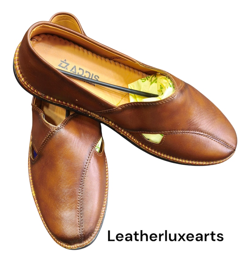 Puede incluir: Un par de zapatos sin cordones de cuero marr&oacute;n con punta y costuras decorativas. Los zapatos tienen un dise&ntilde;o recortado en los laterales y un ribete dorado. La marca "ADDIS" es visible en el interior. El texto "Leatherluxearts" est&aacute; en la parte inferior.