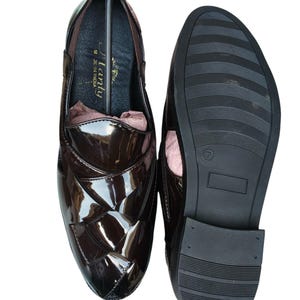 May include: A pair of dark brown patent leather loafers with a woven-style upper design. One shoe shows the interior with the text "Flanty" and "Made in India" printed on the insole, while the other shoe displays the black textured rubber outsole.