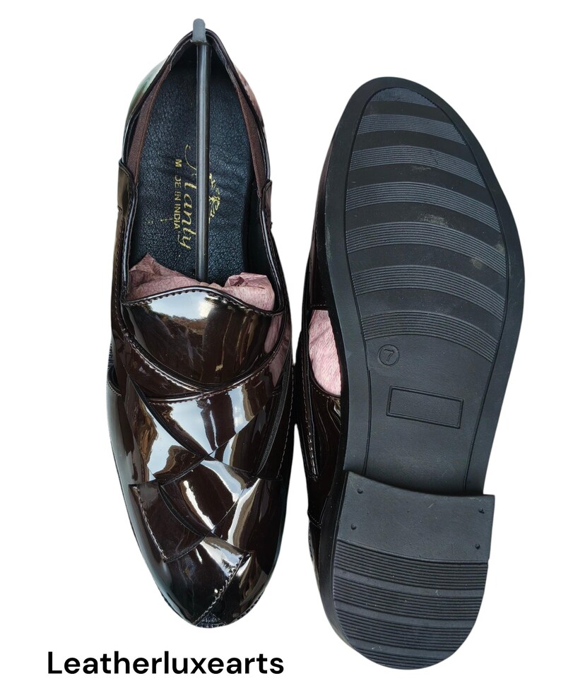 May include: A pair of dark brown patent leather loafers with a woven-style upper design. One shoe shows the interior with the text "Flanty" and "Made in India" printed on the insole, while the other shoe displays the black textured rubber outsole.