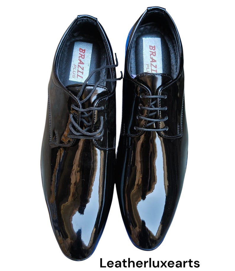 May include: A pair of glossy black leather dress shoes with laces. The shoes have a polished finish and a classic design. The insoles are labeled "BRAZIL PLUS". The image also includes the text "Leatherluxearts".