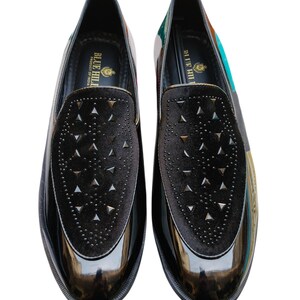 May include: Pair of black patent leather loafers with a velvet vamp featuring triangle-shaped studs. The shoes have a glossy finish and a printed design on the heel. The brand name "BLUE HILL" is visible on the inner sole.