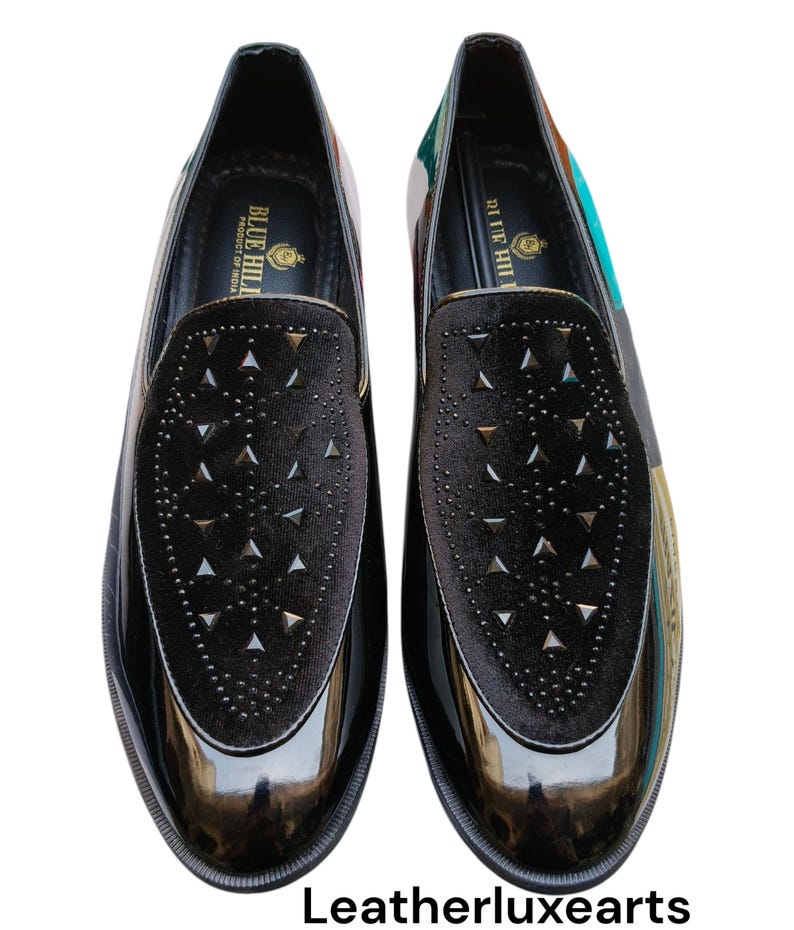 May include: Pair of black patent leather loafers with a velvet vamp featuring triangle-shaped studs. The shoes have a glossy finish and a printed design on the heel. The brand name "BLUE HILL" is visible on the inner sole.