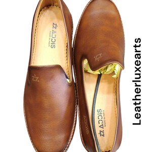 Pu&ograve; includere: Un paio di mocassini in pelle marrone. Le scarpe hanno un aspetto liscio e lucido con punta arrotondata e tacco basso. Il marchio "ADDIS" &egrave; visibile sulla soletta. "MADE IN INDIA".