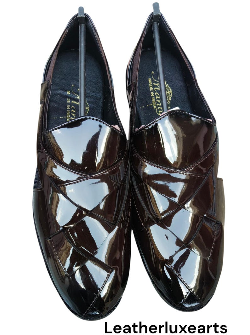 May include: A pair of dark brown, high-gloss loafers featuring a woven-style upper design. The interior of the shoes displays a black insole with the text "Many" and "MADE IN INDIA" printed in gold. The brand name "Leatherluxearts" appears below.