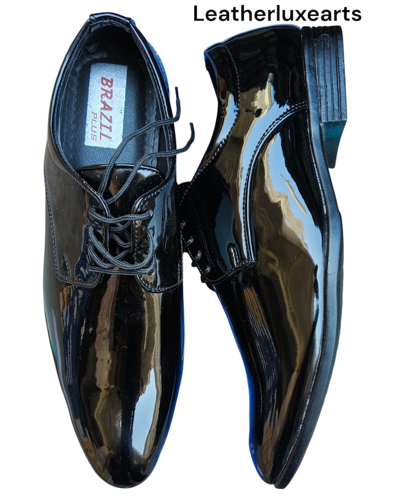 May include: Pair of glossy black dress shoes with laces. The shoes have a shiny patent leather finish and a classic design. The brand name "BRAZIL PLUS" is visible inside one shoe. The shoes are displayed on a white background.