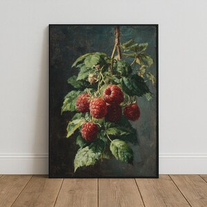 Puede incluir: Una impresión de arte mural rectangular enmarcada que presenta una pintura al óleo detallada de un racimo de frambuesas rojas maduras que cuelgan de un tallo con hojas verdes sobre un fondo oscuro y sombrío. La obra está en un marco negro fino.