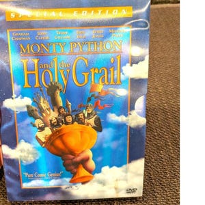 以下が含まれることがあります： Monty Python and the Holy GrailのDVDケース。青い空と白い雲を背景に、手で持たれた大きな金の聖杯とキャストのイラストが描かれています。テキストにはSpecial Edition, Monty Python and the Holy Grailと記されています。