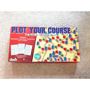 May include: Plot Your Course board game box featuring a red and beige map design. The box displays the title, game contents, and three levels of play for grades 2-5. It includes illustrations of a bicycle, airplane, ship, and geometric shapes.