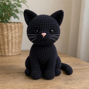 May include: A black crocheted cat figurine featuring a small pink stitched nose, two large glossy black plastic eyes, and thin white thread whiskers. The cat is depicted in a seated position with its tail curled to the side, showcasing a textured yarn construction throughout its entire body.