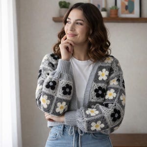 May include: A white ceramic mug with a black handle and the text "But First, Coffee" in a bold, black font. The mug is filled with a dark liquid, likely coffee, and sits on a light-colored surface.