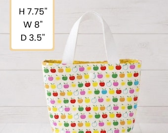 May include: A small tote bag with a white handle and a colorful apple pattern. The bag is 7.75 inches high, 8 inches wide, and 3.5 inches deep. The interior is yellow.