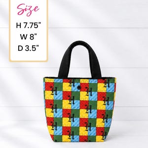 May include: A colorful tote bag with a patchwork design. The bag features a black handle and a button closure. The bag is 7.75 inches high, 8 inches wide, and 3.5 inches deep.