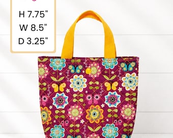 May include: A small tote bag with a floral pattern in shades of purple, teal, yellow, and pink. The bag has yellow handles and the dimensions are H 7.75", W 8.5", and D 3.25". The bag is decorated with flowers and butterflies.