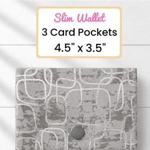 May include: A gray slim wallet with a geometric pattern and a button closure. The wallet has 3 card pockets and measures 4.5" x 3.5". The text "Slim Wallet" and "3 Card Pockets 4.5" x 3.5"" is displayed on a white background.