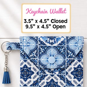 May include: Blue and white patterned keychain wallet with a matching tassel. Closed, it measures 3.5" x 4.5". Open, it measures 9.5" x 4.5". The wallet has a button closure and a silver keychain.