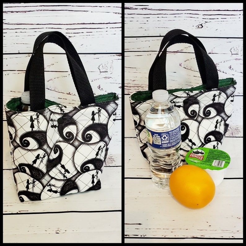 May include: A black and white lunch bag with a repeating pattern of Jack Skellington and Sally from The Nightmare Before Christmas. The bag has a black handle and a green lining. The bag is shown with a water bottle, an orange, and a container of Pringles.