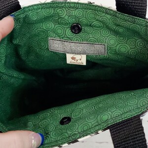 May include: A green and white fabric tote bag with black straps. The inside of the bag is lined with a green fabric with a circle pattern. A label sewn into the inside of the bag reads "Black Bear Gifts" and "Handmade".