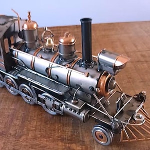 Puede incluir: Una taza de cerámica blanca con un asa negra y el texto "But First, Coffee" en negro y negrita. La taza está sobre una superficie blanca. La taza mide aproximadamente 10 cm de alto.