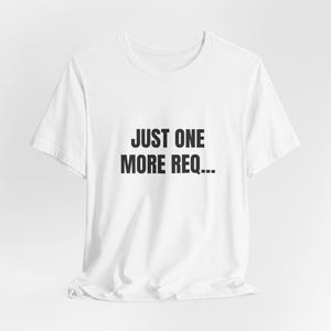 May include: White t-shirt with the text "JUST ONE MORE REQ..." printed in black. The shirt has a crew neck and short sleeves. The fabric appears to be a soft cotton blend.