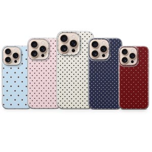 May include: A collection of five phone cases in various colors: light blue, pink, off-white, navy, and burgundy. Each case features a repeating pattern of small black polka dots. The cases have a clear border around the camera.