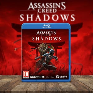 May include: A blue Blu-ray case for the video game "Assassin's Creed Shadows" is shown on a wooden surface. The cover art depicts two figures in combat against a red backdrop with Japanese architecture. The game title is clearly visible.