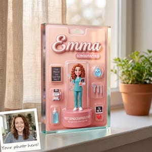 May include: A custom acrylic display featuring a figurine of a sonographer named Emma in teal scrubs. The pink backing includes accessories like a monitor, ultrasound probe, baby icon, and text reading Emma, Sonographer, and Best Sonographer Ever.