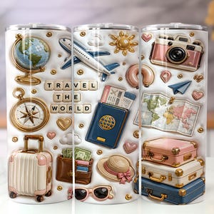 May include: A white cylindrical tumbler featuring a travel-themed design with a globe, aeroplane, camera, compass, passport, map, and stacked suitcases. The text "TRAVEL THE WORLD" is displayed in a block-letter style, surrounded by small hearts and gold dots.