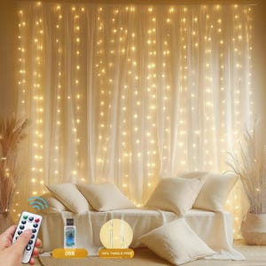 May include: A warm, inviting scene featuring a sheer curtain illuminated by numerous small, twinkling lights. A sofa with cream-colored pillows and a blanket is in front of the curtain. A remote control, a USB connector, and a graphic that says "100% TANGLE-FREE" are also visible.