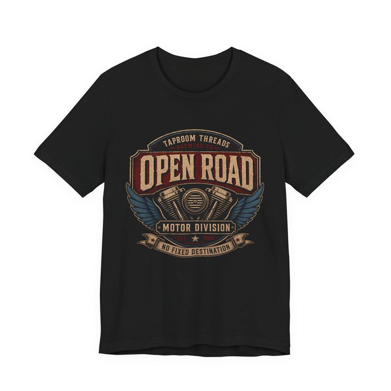 May include: Black t-shirt featuring a vintage-style graphic with the words "Open Road" in a distressed font. The design includes a motorcycle engine, wings, and the text "Motor Division" and "No Fixed Destination."