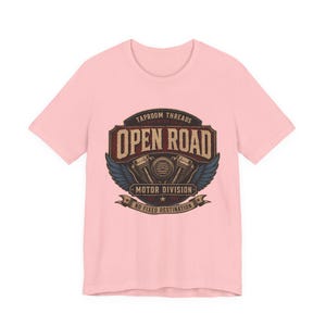 May include: A light pink t-shirt featuring a vintage-style graphic. The graphic includes the words "TAPROOM THREADS" and "OPEN ROAD MOTOR DIVISION" with a motorcycle engine illustration and the phrase "NO FIXED DESTINATION".