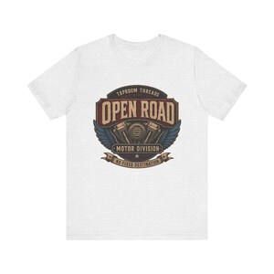 May include: A light gray t-shirt featuring a vintage-style graphic. The graphic includes the text "TAPROOM THREADS OPEN ROAD MOTOR DIVISION NO FIXED DESTINATION" with a motorcycle engine design and wings.