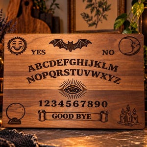 May include: A rectangular wooden spirit board featuring laser-engraved designs including a sun, a bat, a moon, an eye, a crystal ball, and candles. The board displays the alphabet, numbers 0 through 9, the words YES, NO, and GOOD BYE.