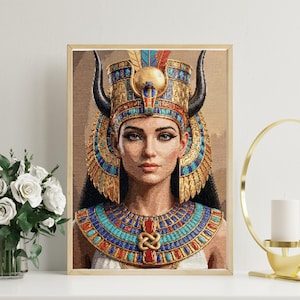 May include: A framed portrait of an Egyptian queen. The artwork features a woman wearing a gold headdress with black horns, a blue and gold collar, and a white dress. The portrait is displayed on a white surface with a vase of white flowers and a gold candle holder.