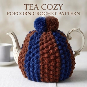 Puede incluir: Un calentador de té de ganchillo de palomitas de maíz azul y marrón cubre una tetera blanca. El calentador tiene dos pompones en la parte superior y rayas verticales. El texto "TEA COZY POPCORN CROCHET PATTERN" está en la parte superior de la imagen.