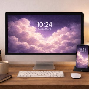 Könnte beinhalten: Ein moderner Schreibtisch mit einem Computermonitor, Smartphone, Tastatur und Maus. Die Bildschirme zeigen eine lila Wolkenlandschaft und die Uhrzeit 10:24. Eine Kaffeetasse, ein Notizbuch und eine Lampe befinden sich ebenfalls auf dem Schreibtisch.