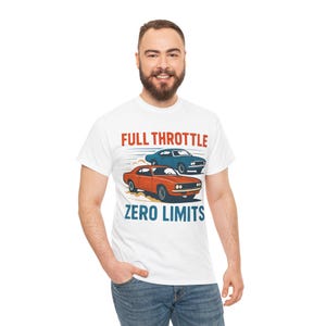 Könnte beinhalten: Weißes T-Shirt mit einer Retro-Illustration von zwei klassischen Autos, einem orangefarbenen und einem blauen, mit dem Text "FULL THROTTLE ZERO LIMITS" in Rot und Blau. Das Design erinnert an Geschwindigkeit und Vintage-Automobil-Stil.