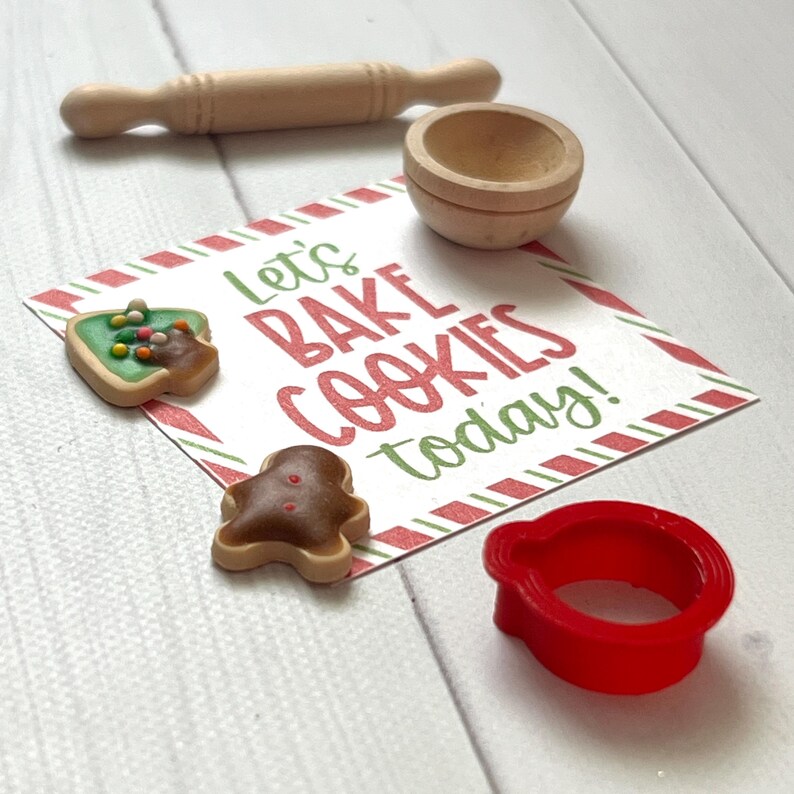 May include: A miniature baking set with a rolling pin, bowl, and cookie cutters. The set includes two decorated cookies and a card that reads "Let's BAKE COOKIES today!" in red and green lettering.
