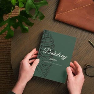 Puede incluir: Un diario verde titulado "Radiology Journal" con una ilustración de la caja torácica. El diario está sostenido por manos sobre una mesa de madera, con una cartera de cuero y una planta en el fondo. El diario también tiene las palabras "CREATE - ANALYZE - DIAGNOSE".