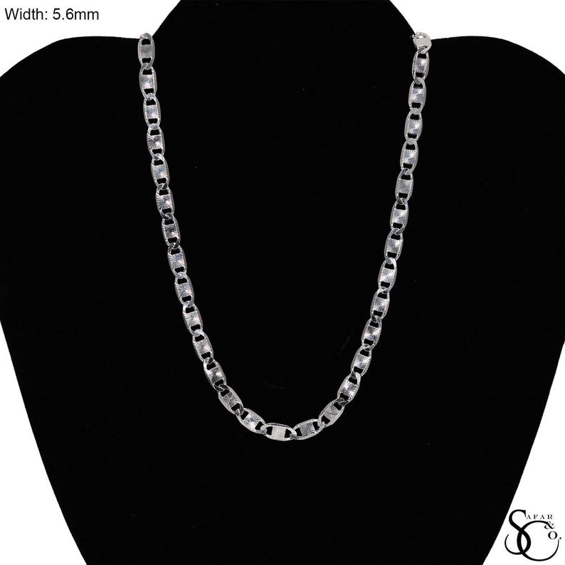 May include: A silver-colored chain necklace with a width of 5.6mm. The necklace is displayed on a black mannequin. The chain links are rectangular and connected in a repeating pattern. The necklace is a jewelry item.