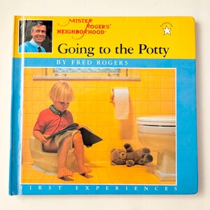 May include: A children's book titled "Going to the Potty" by Fred Rogers. The cover features a photo of Fred Rogers and an illustration of a child sitting on a potty, reading a book. The book is yellow and blue.